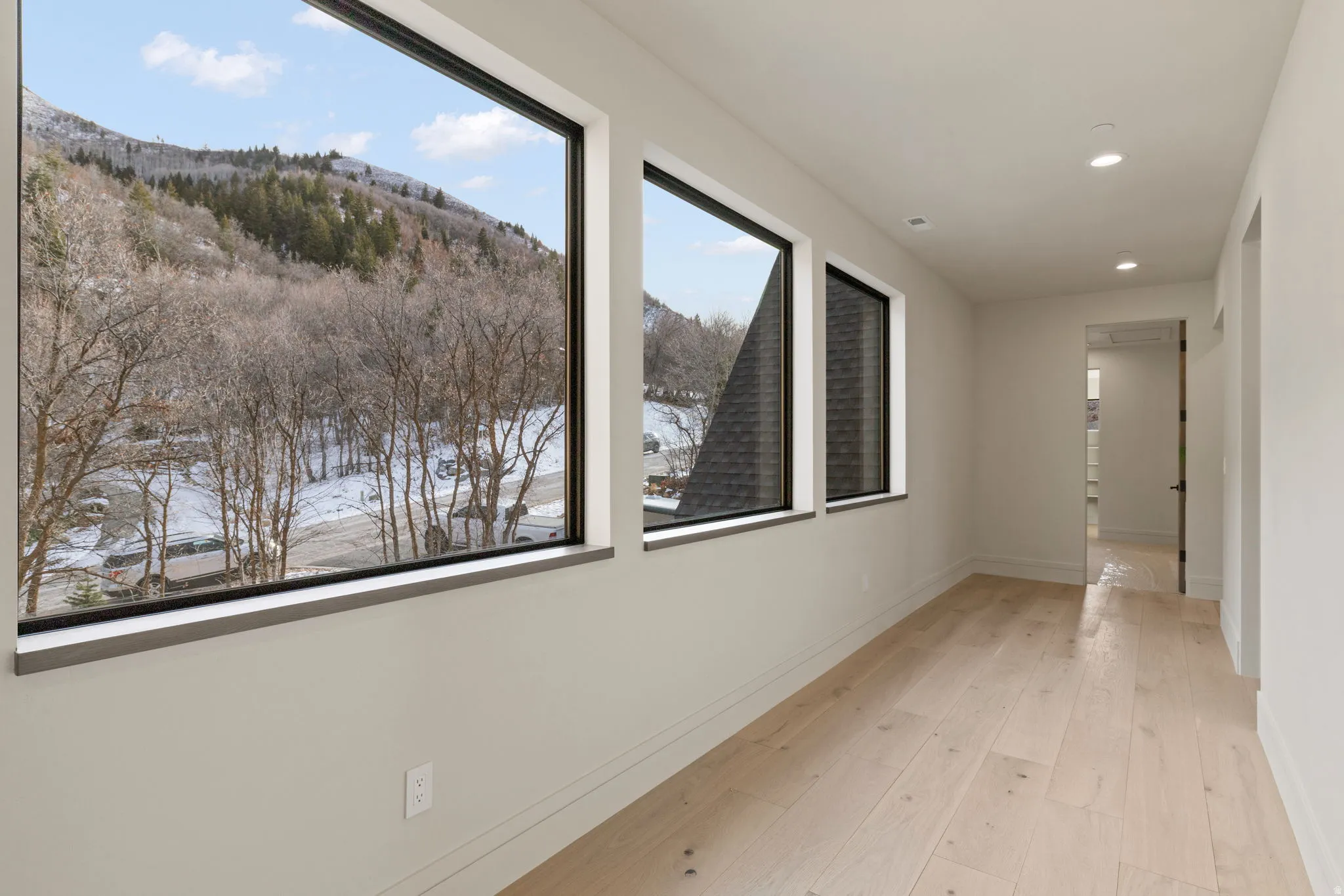 Hall with a mountain view, light wood finished floors, and recessed lighting