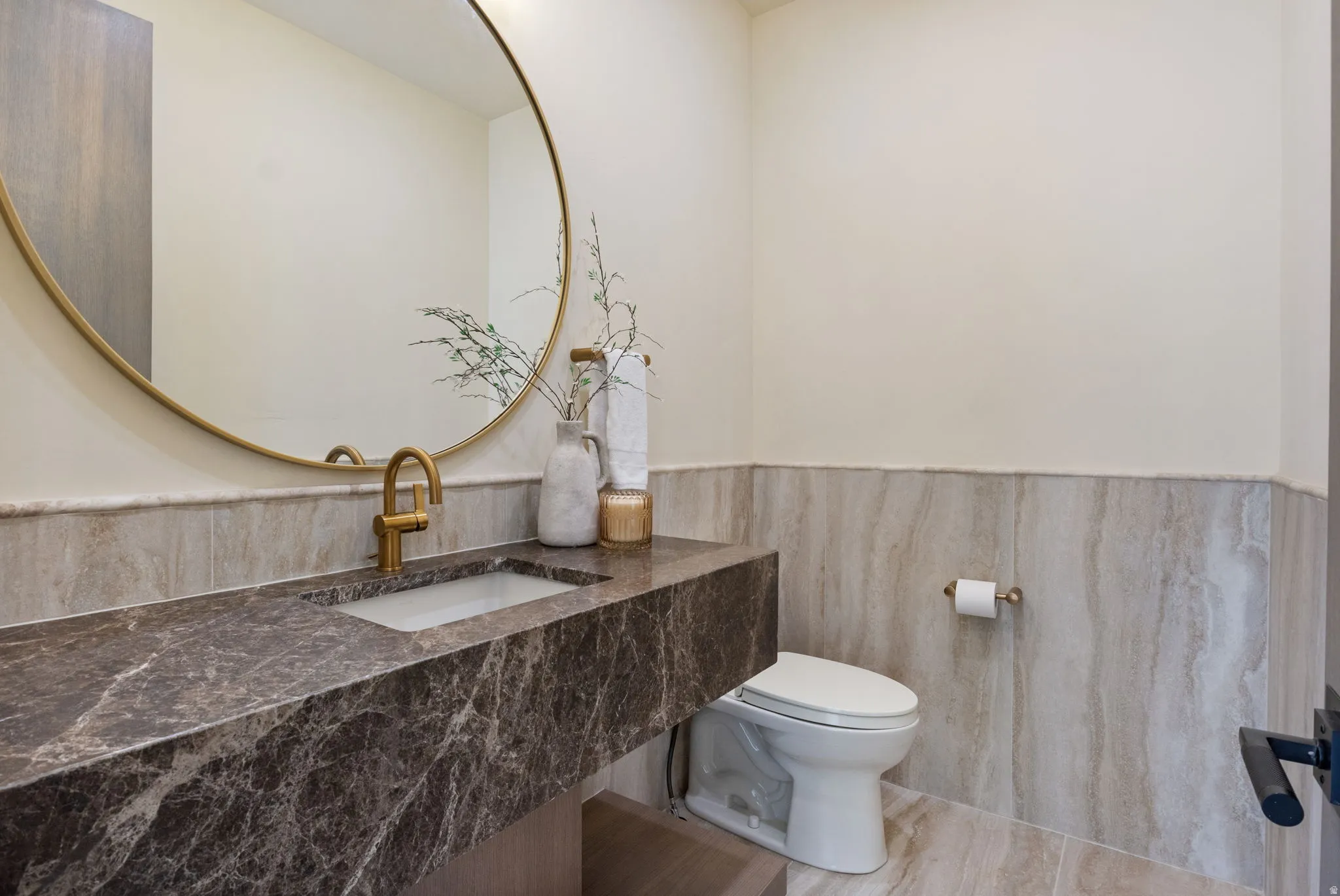 Half bath with vanity, a wainscoted wall, and tile walls