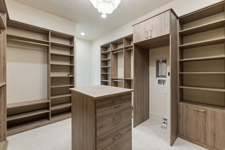 Primary Bedroom Walk in closet featuring an alabaster chandelier and built-in laundry.