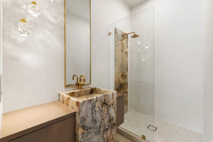 Guest bathroom featuring white oak cabinetry, a free standing sink make from Patagonia quartzite, a walk in shower in artisanal plaster, highlighted with a slab of Patagonia quartzite