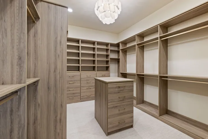 Primary Bedroom Walk in closet featuring an alabaster chandelier and built-in laundry.
