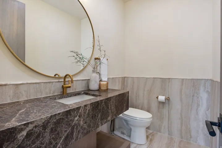 Half bath with vanity, a wainscoted wall, and tile walls