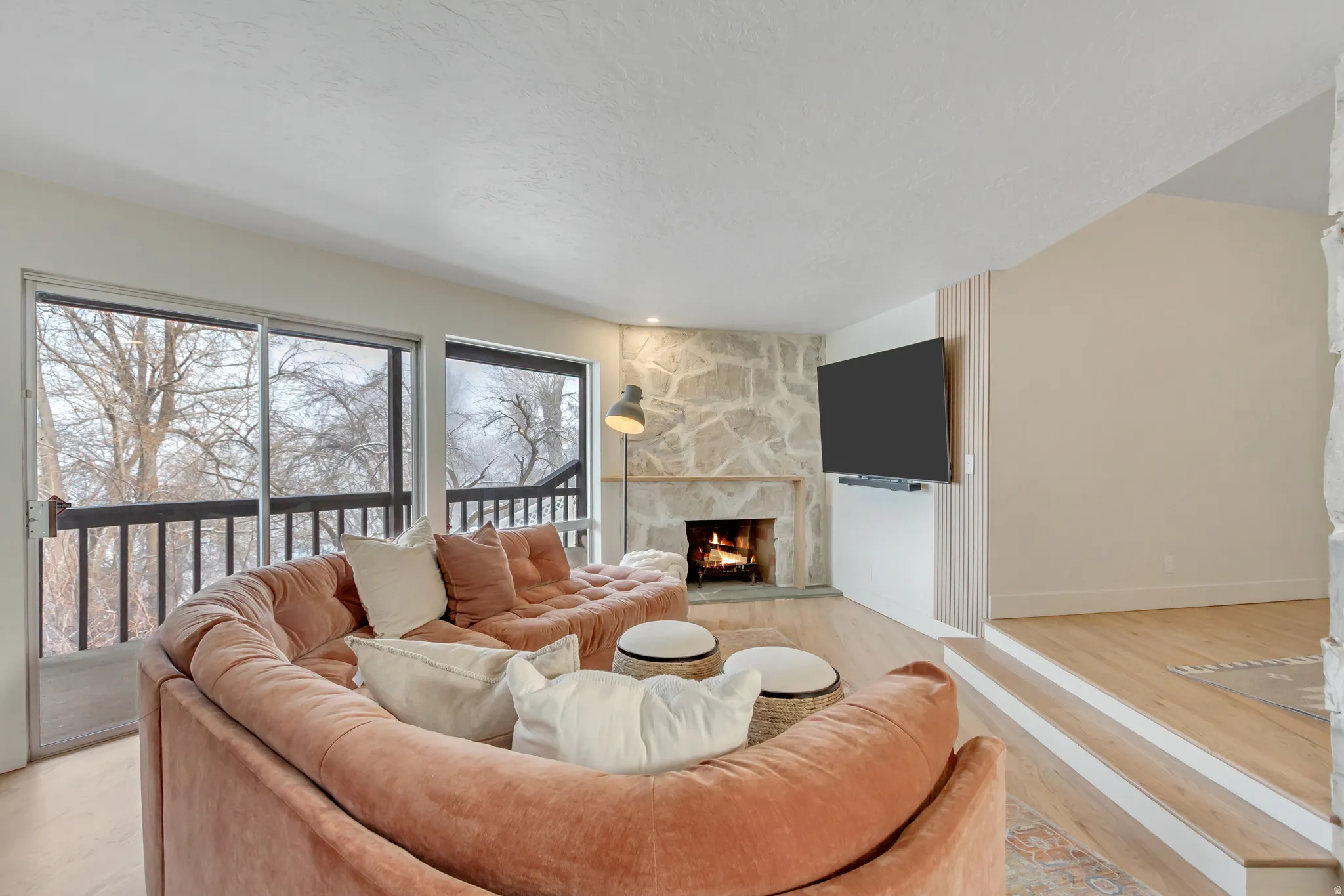 Living area with a premium fireplace, light wood-style flooring, and a textured ceiling