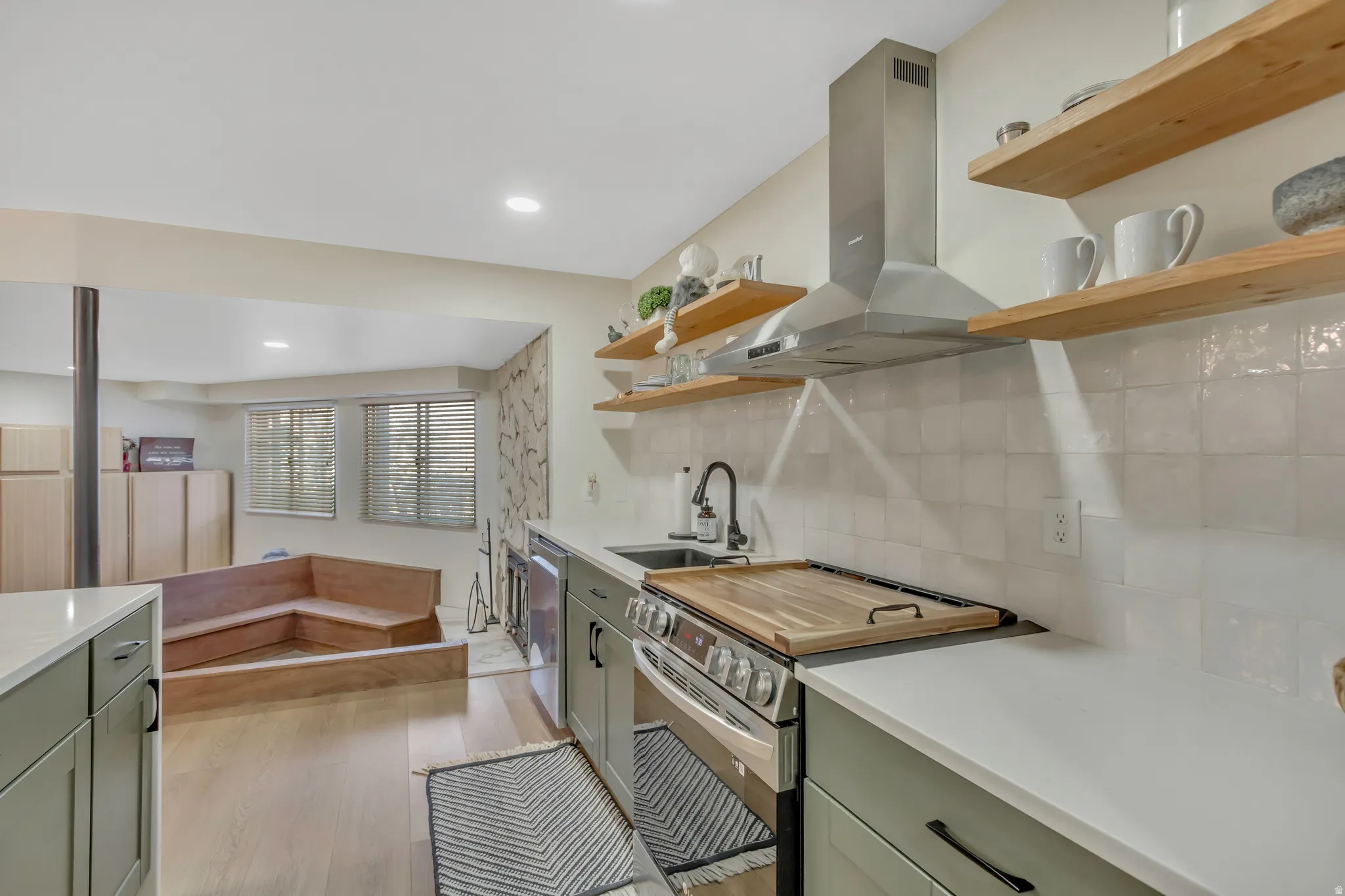 Kitchen with open shelves, stainless steel appliances, island exhaust hood, tasteful backsplash, and light wood-style flooring