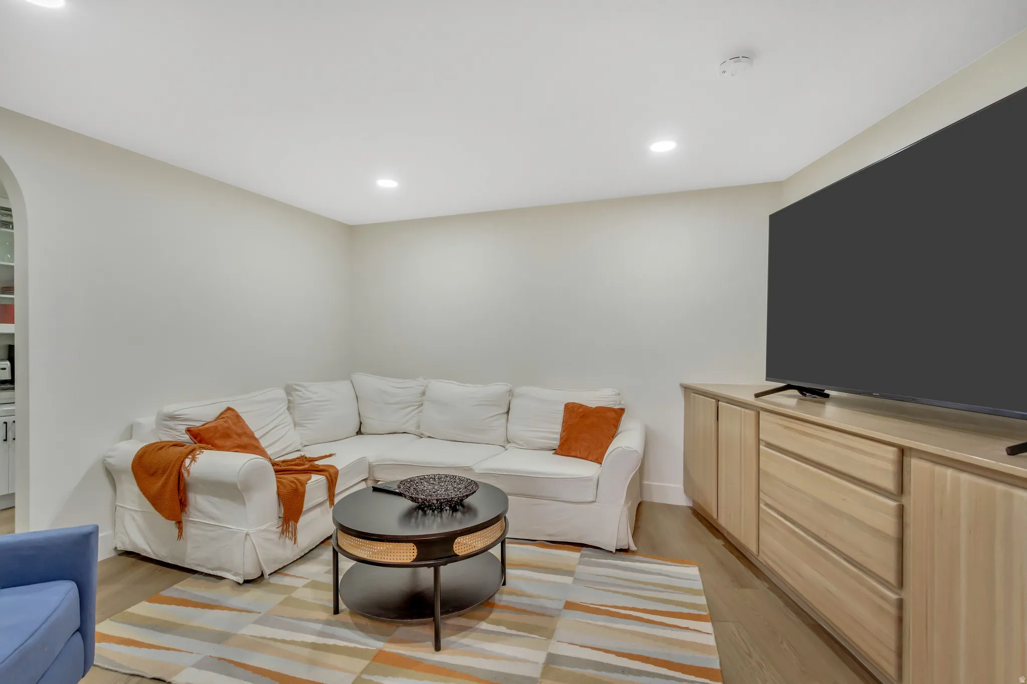 Living room featuring recessed lighting, light wood-style flooring, and arched walkways