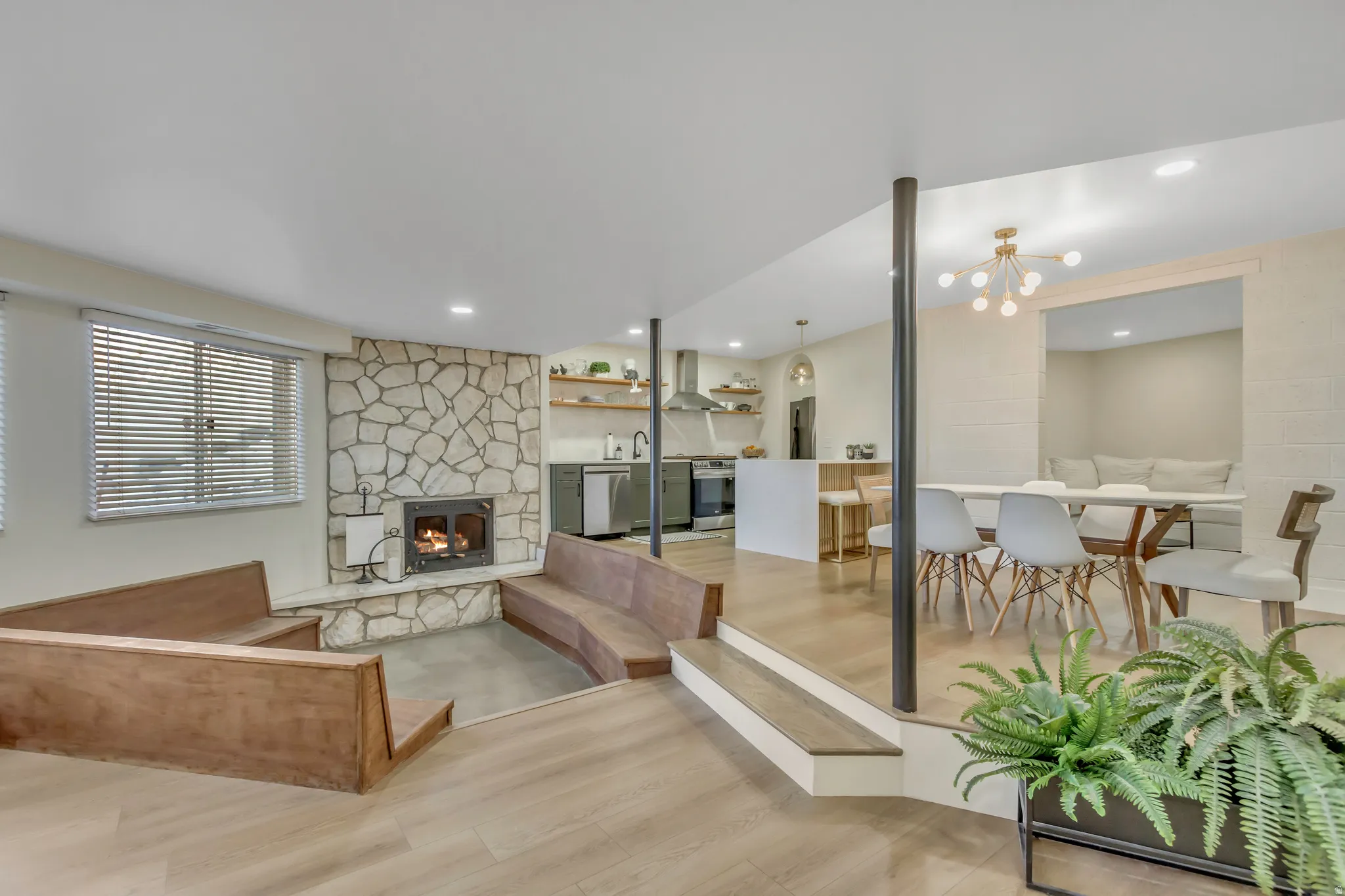 Living room featuring light wood-type flooring, a chandelier, and a fireplace