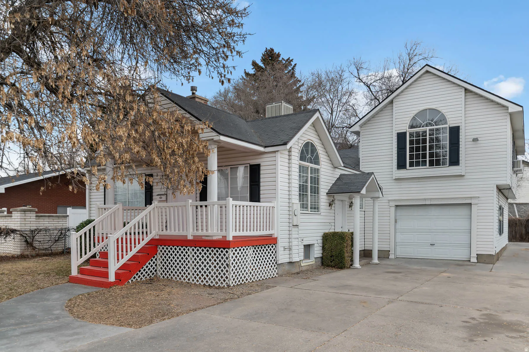 View of front facade with driveway, a deck, an attached garage, and roof with shingles