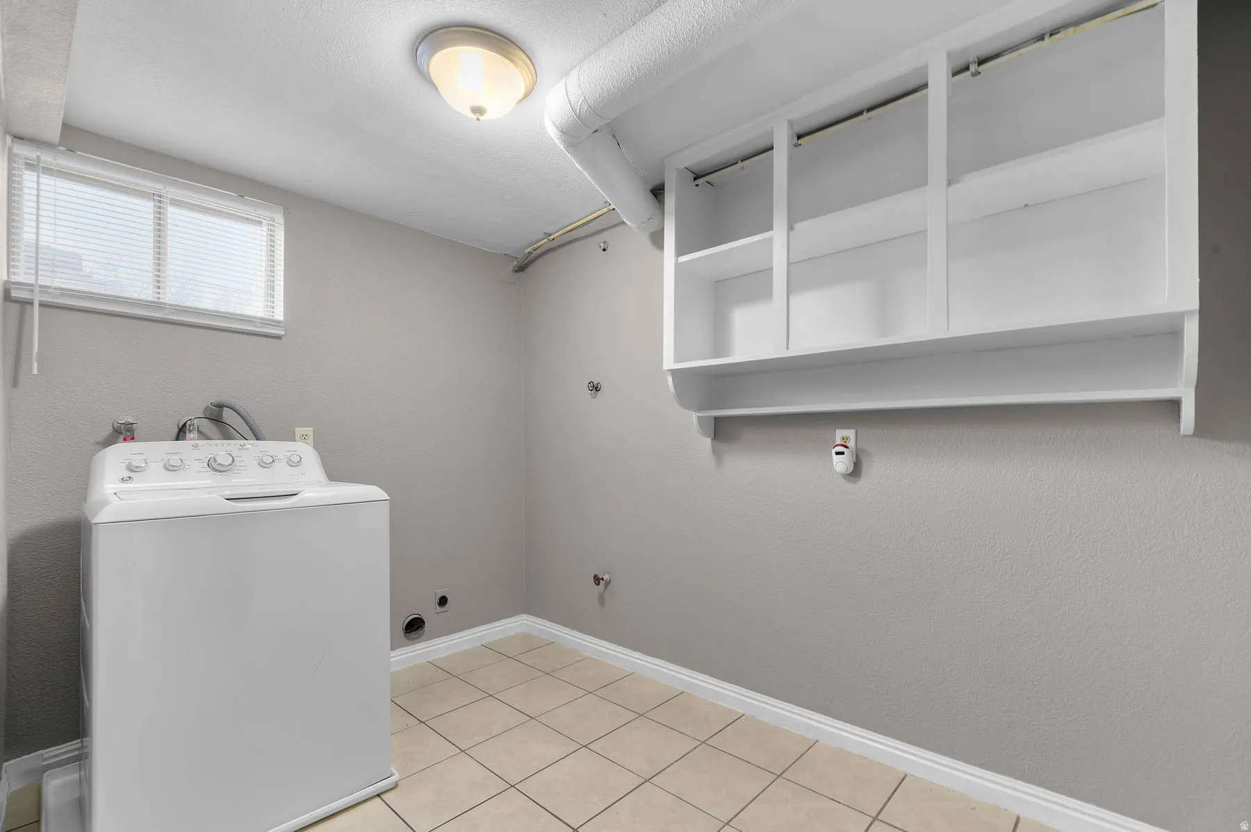 Laundry area with washer / clothes dryer and a textured wall