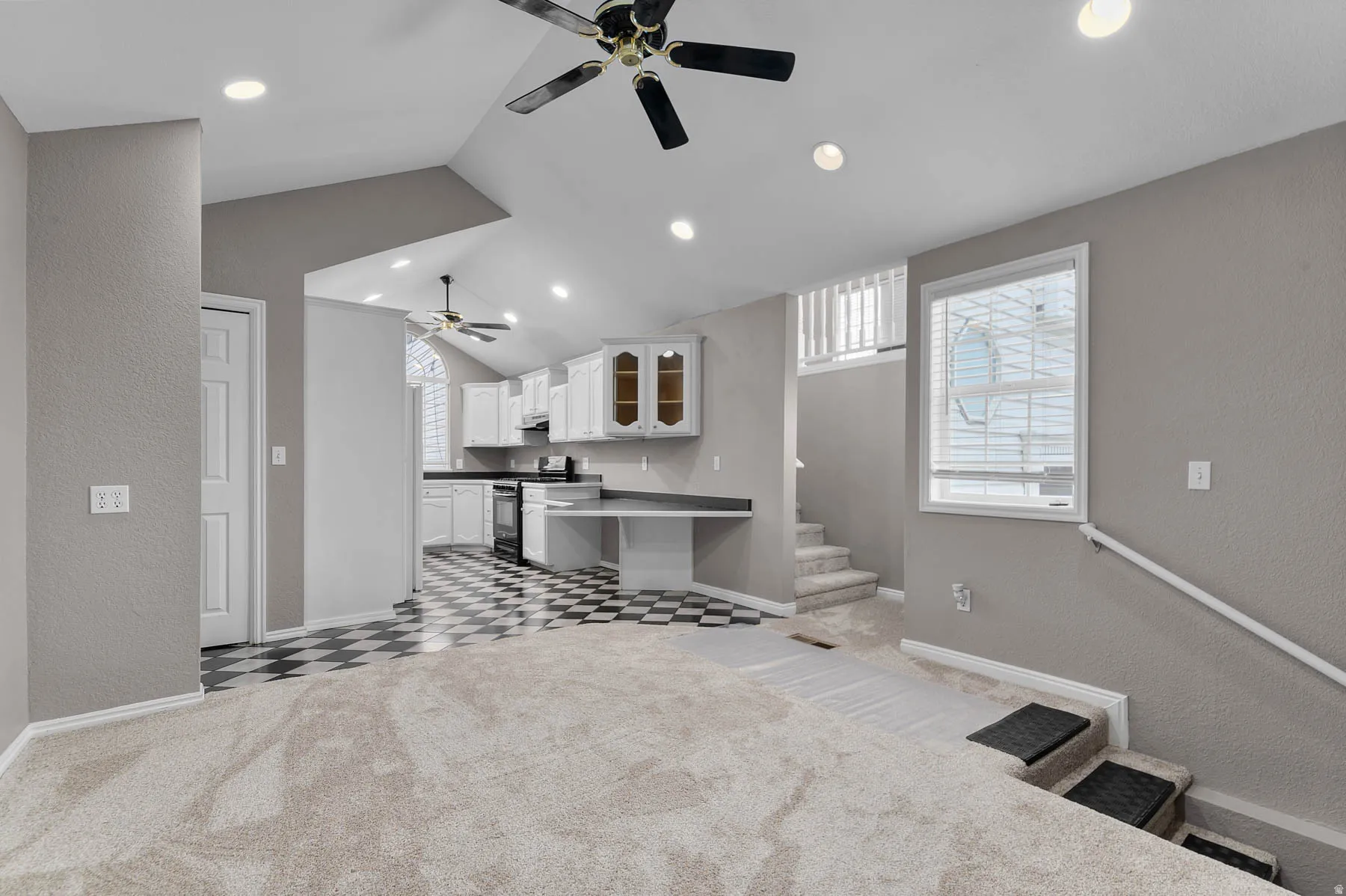 Kitchen featuring open floor plan, a textured wall, glass insert cabinets, a kitchen bar, and white cabinets
