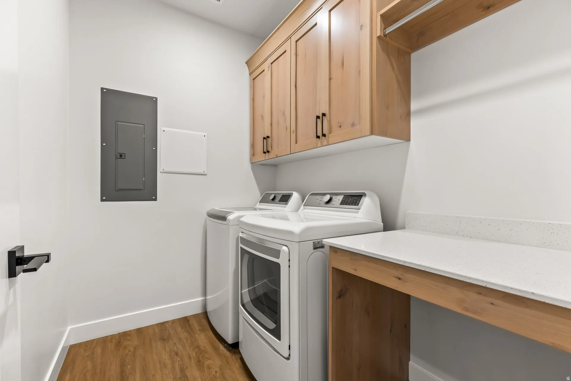 Laundry room featuring electric panel, dark wood-type flooring, separate washer and dryer, and cabinet space