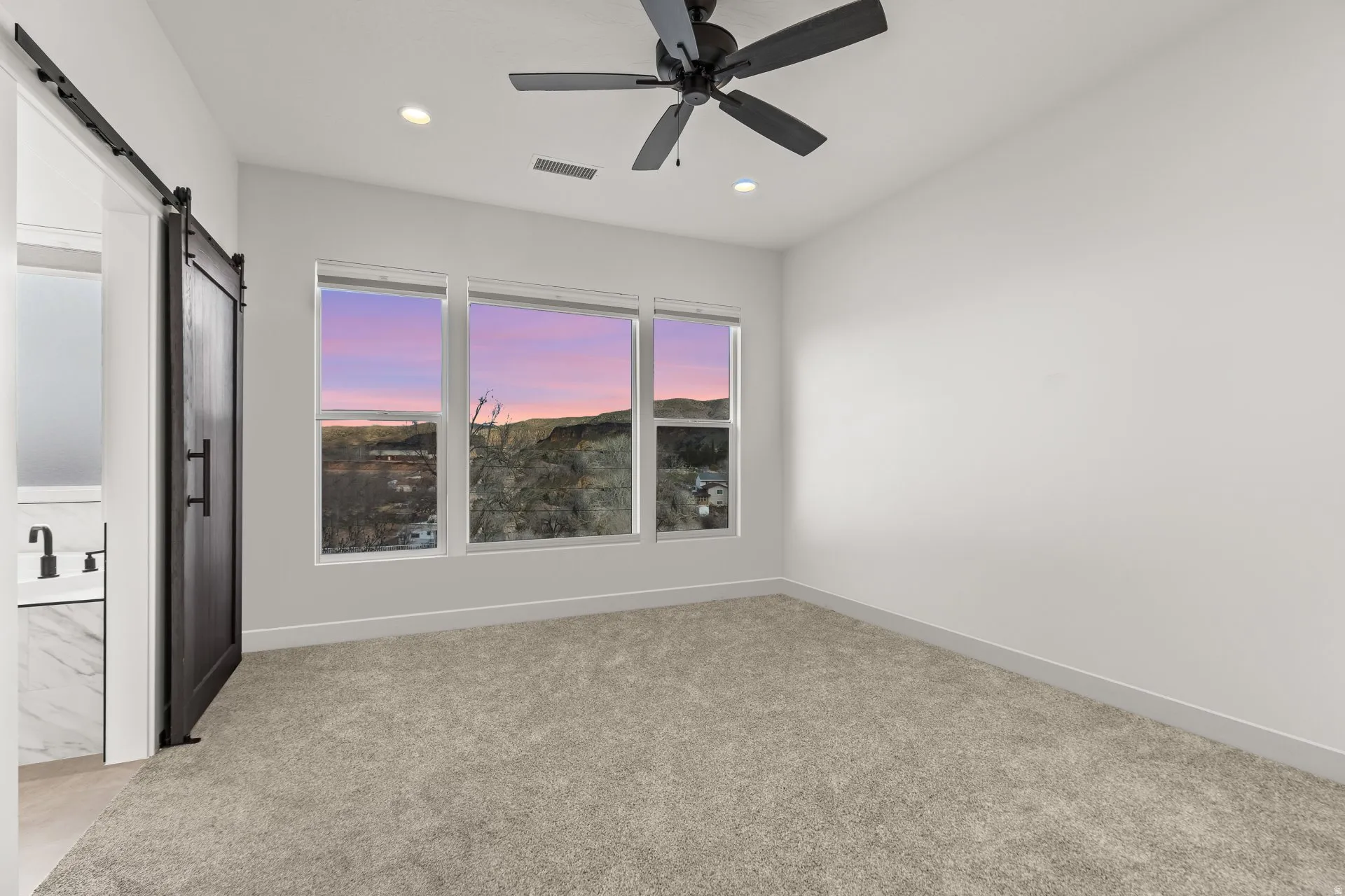 Spare room featuring a barn door, light carpet, recessed lighting, and a ceiling fan