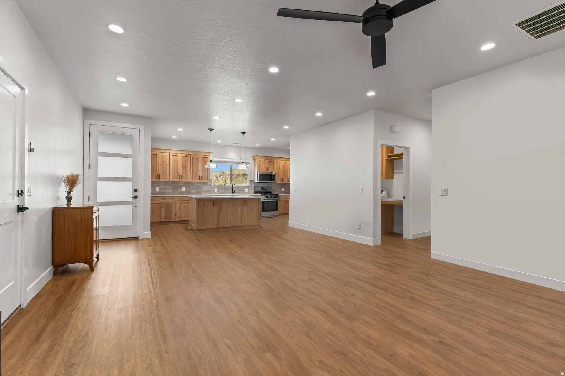 Kitchen featuring decorative light fixtures, open floor plan, a center island, light countertops, and wood finish cabinetry