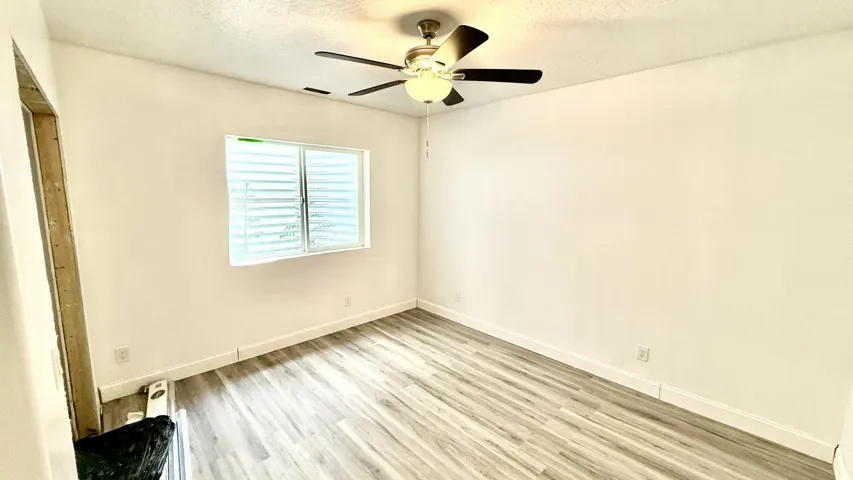 Bright room featuring wood-finish flooring and a ceiling fan with integrated lighting