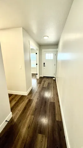 Welcoming entry hall featuring wood-finish flooring, crisp white trim, and a contemporary front door with clear glass inserts