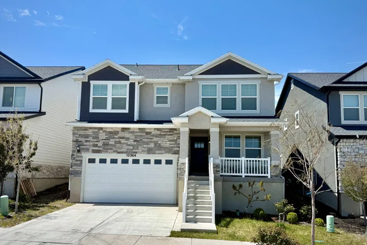 Contemporary two-story residence featuring a stone veneer facade, a two-car garage, and a covered front porch with white railing