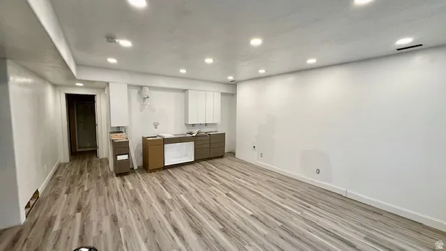 Spacious interior featuring wood-finish flooring, recessed ceiling lighting, and crisp white walls