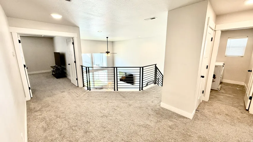 Loft area featuring a modern black metal railing, neutral carpet flooring, and recessed lighting
