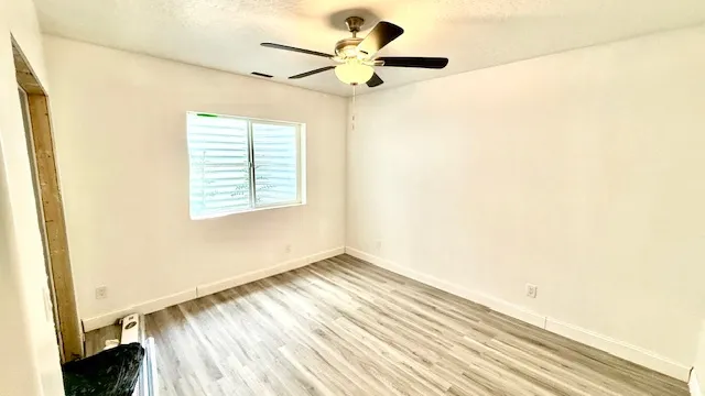 Light-toned wood-finish flooring, white walls, and a ceiling fan with integrated lighting