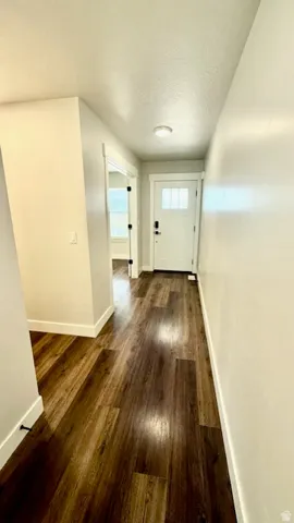 Entryway featuring rich wood-finish flooring, white trim, and light-toned walls