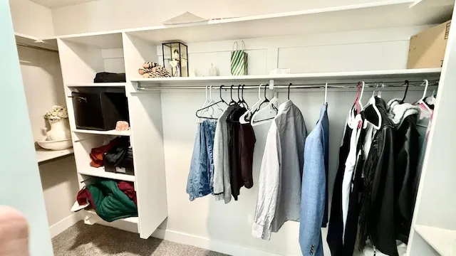Primary Suite Built-in closet system featuring white shelving, multiple hanging rods, and integrated storage compartments