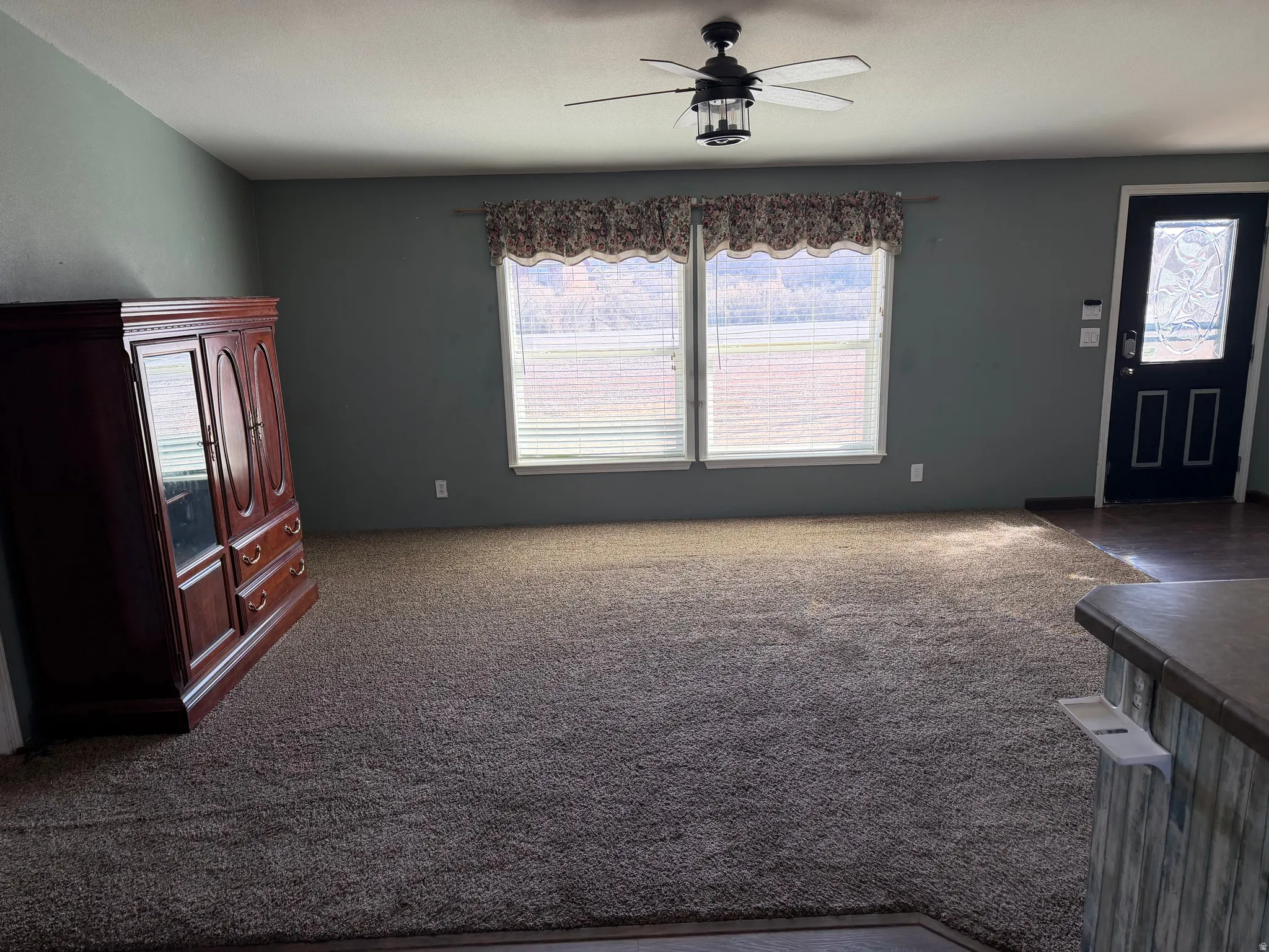 Entrance foyer featuring dark colored carpet and ceiling fan