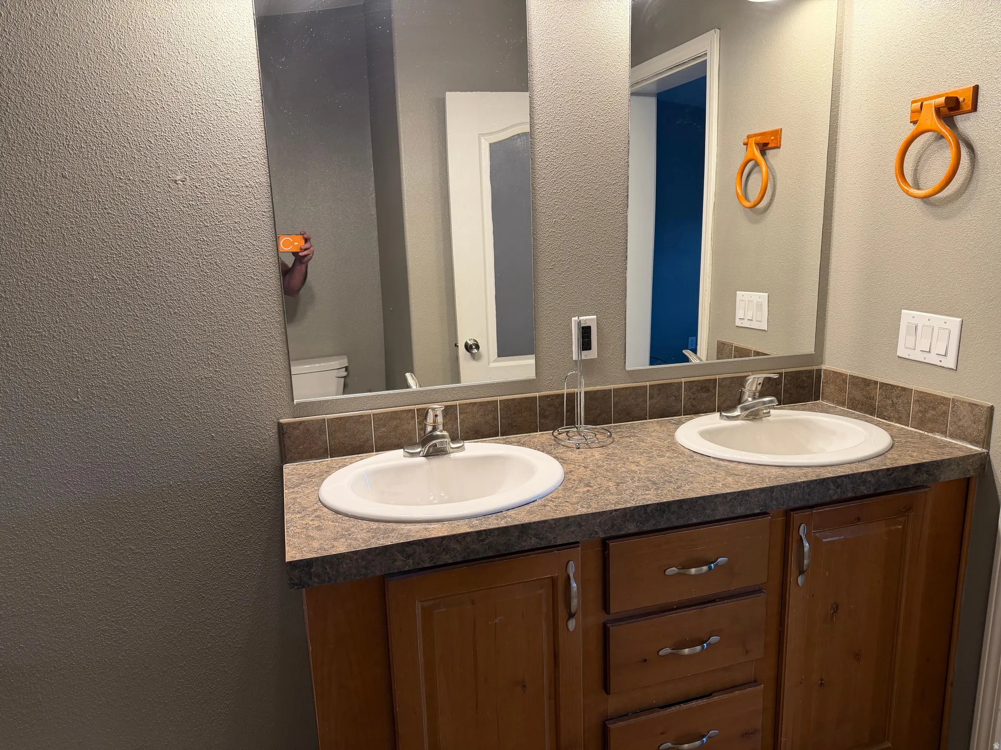 Bathroom with a textured wall and double vanity