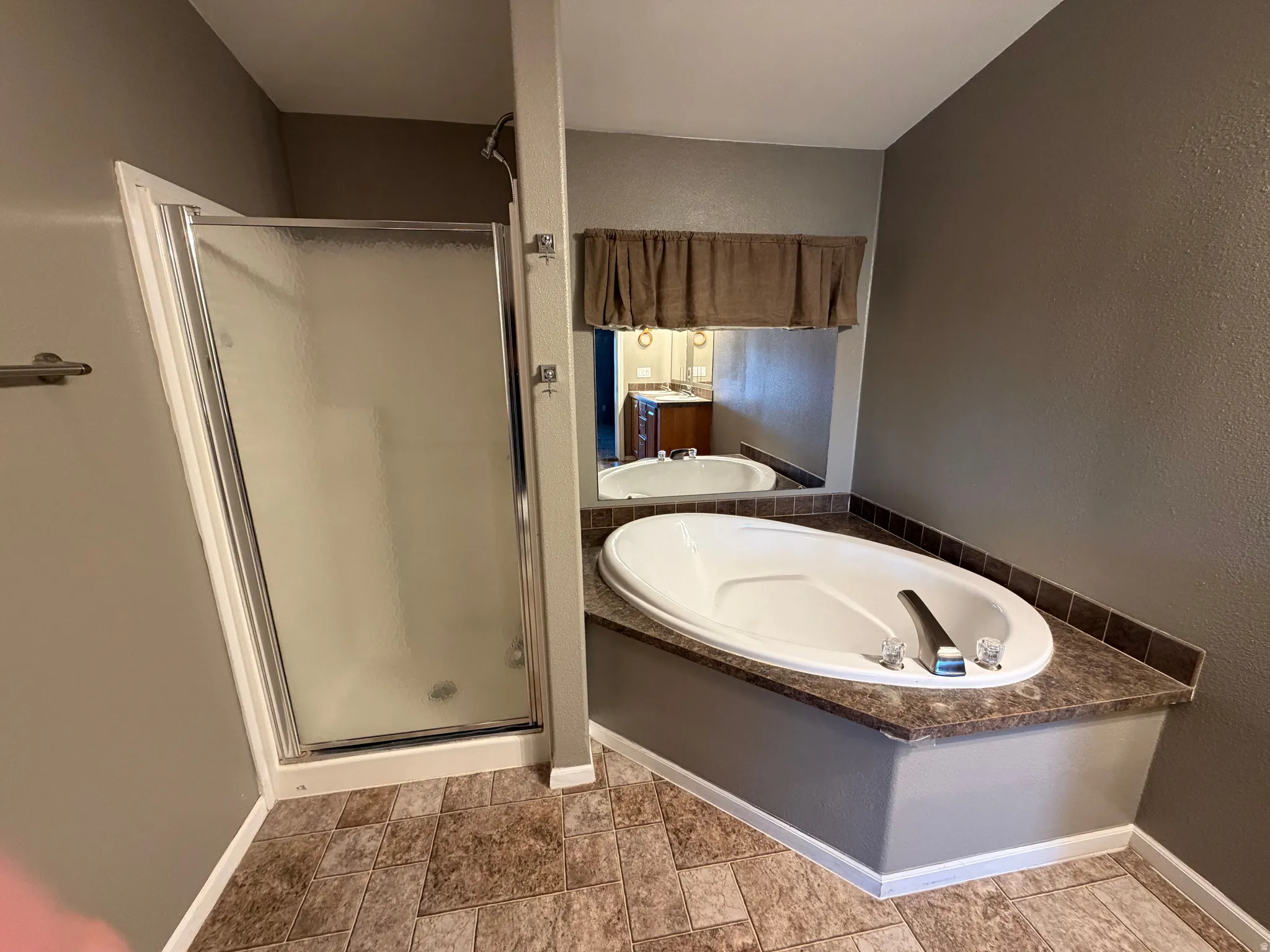 Bathroom with a stall shower, a garden tub, and a textured wall