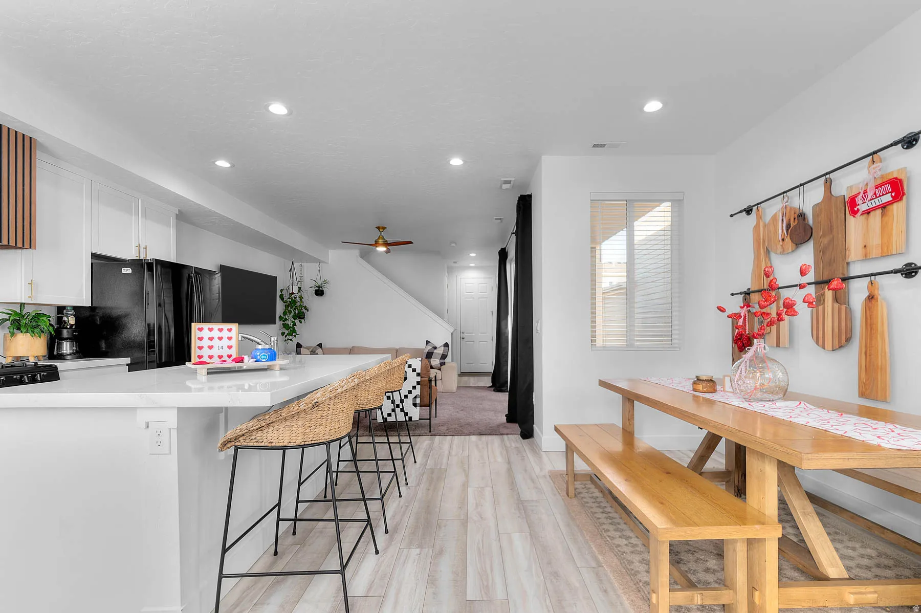 Kitchen featuring white cabinets, a kitchen bar, light wood-style floors, freestanding refrigerator, and light stone countertops