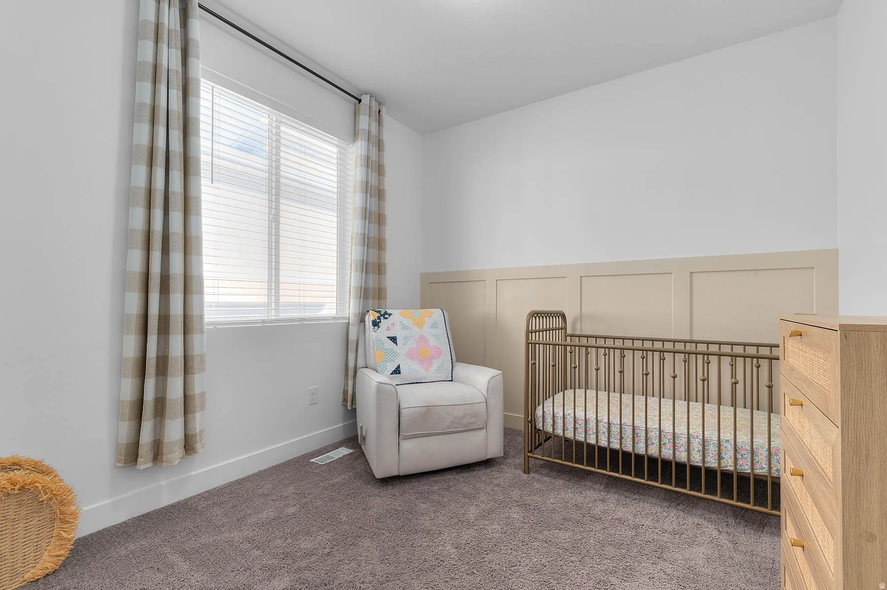 Bedroom with a nursery area, a decorative wall, carpet floors, and a wainscoted wall
