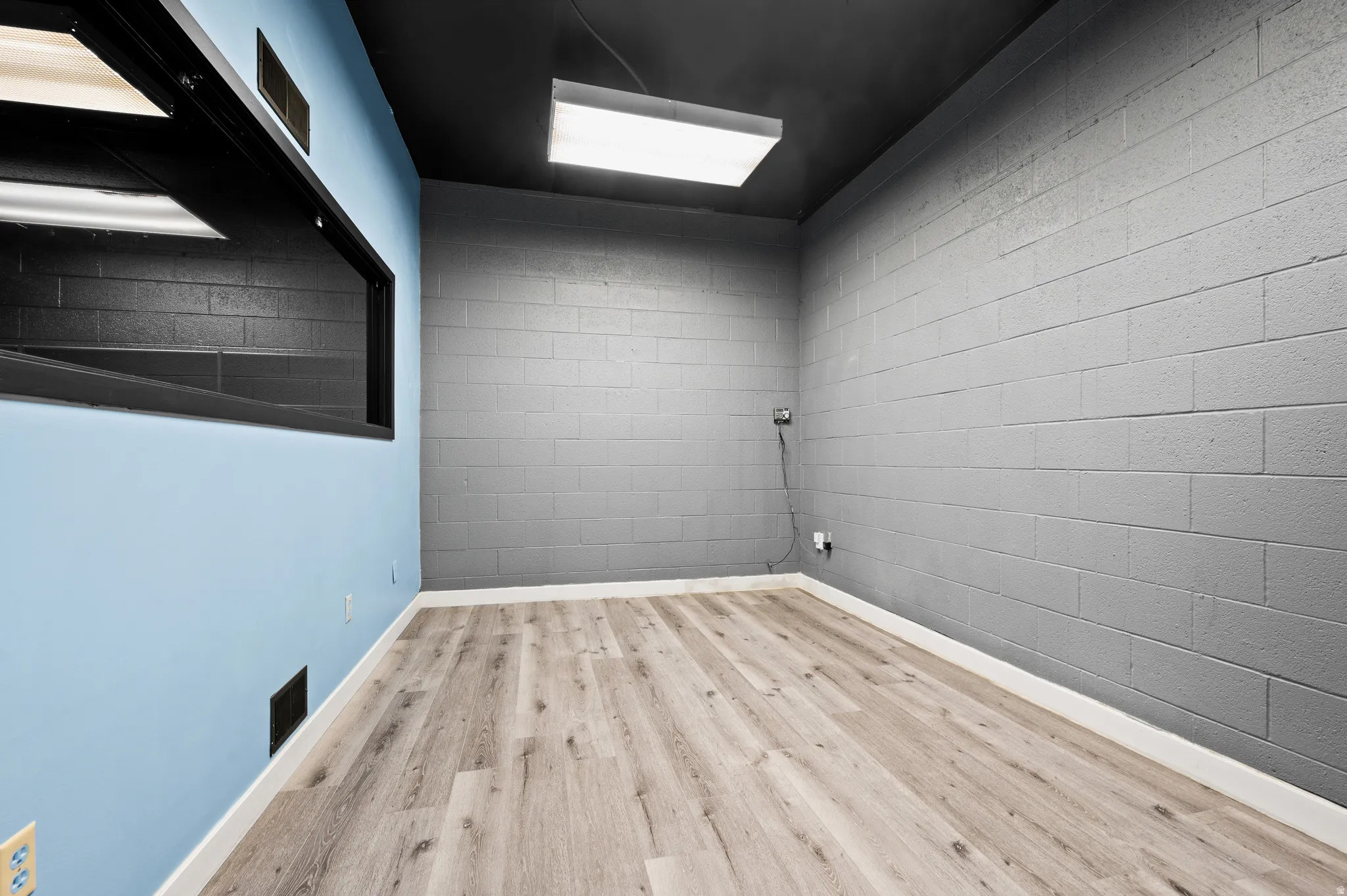 Empty room with concrete block wall and wood finished floors