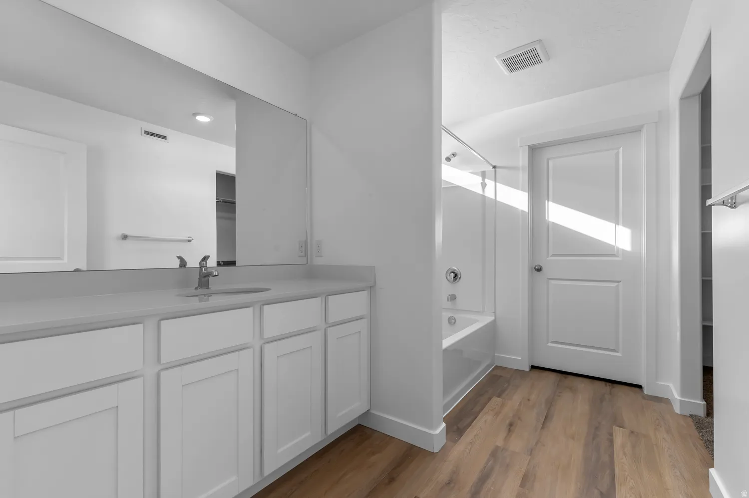 Full bath featuring vanity, light wood finished floors, tub / shower combination, and a spacious closet