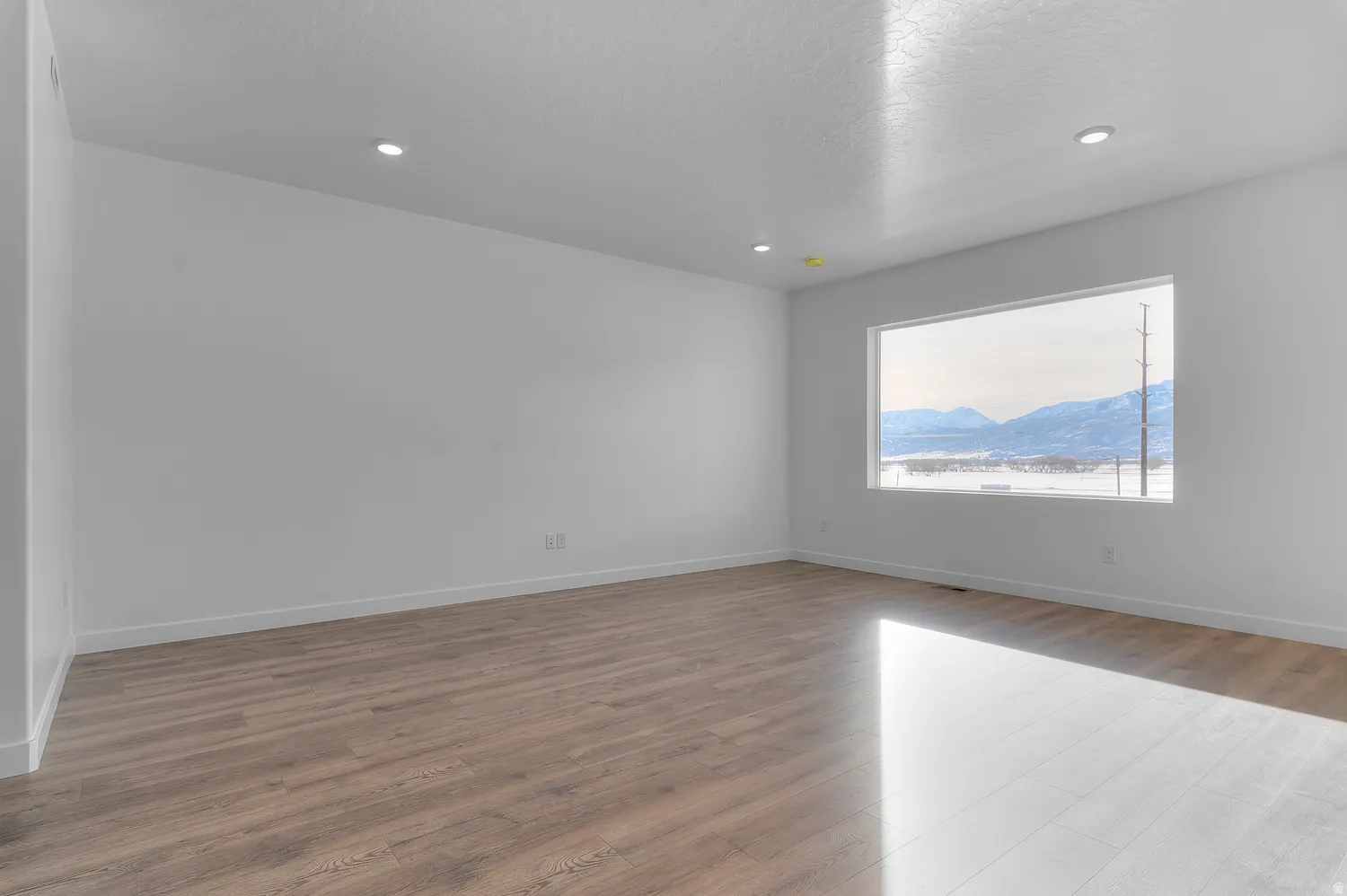 Unfurnished room with dark wood-style flooring, a mountain view, and recessed lighting