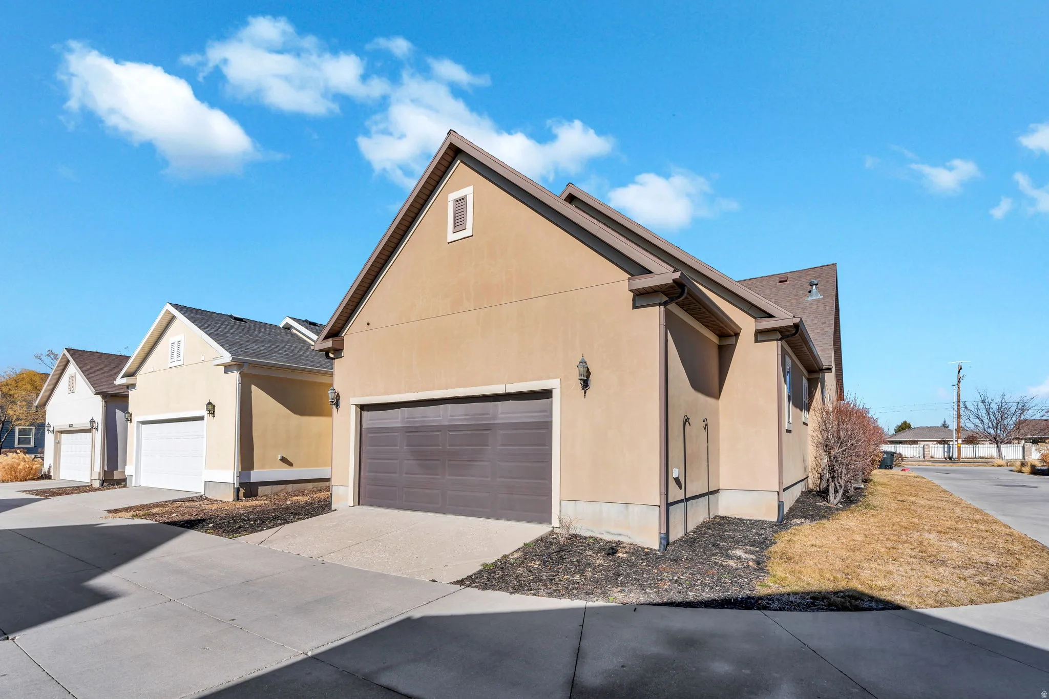 View of side of home with concrete driveway, stucco siding, an attached garage, and a residential view