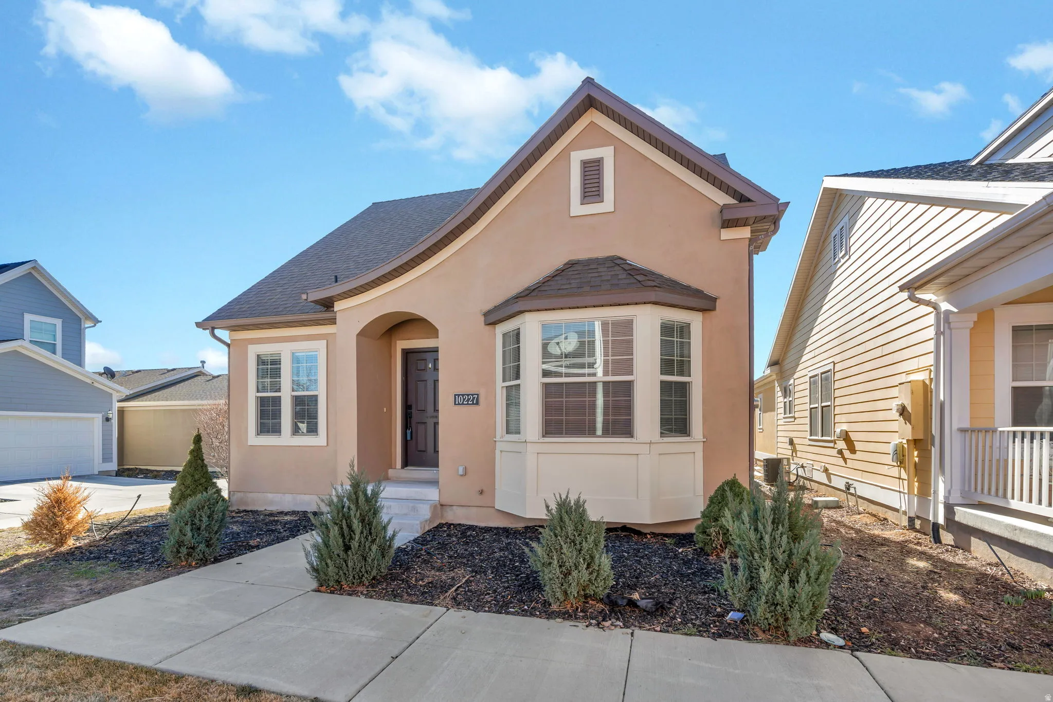View of front facade with stucco siding and a shingled roof