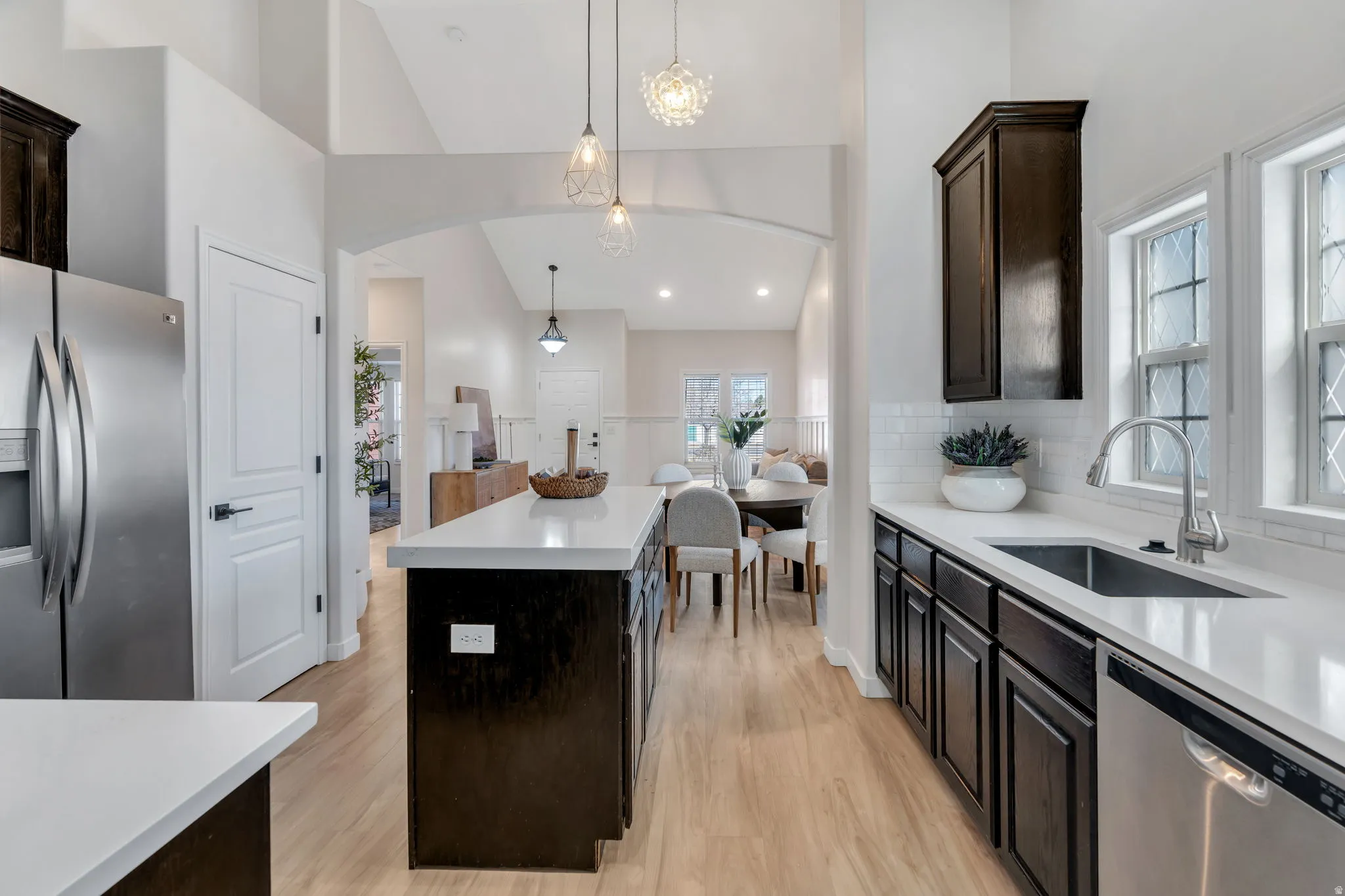 Kitchen with a center island, stainless steel appliances, dark wood finish cabinetry, light wood finished floors, and backsplash