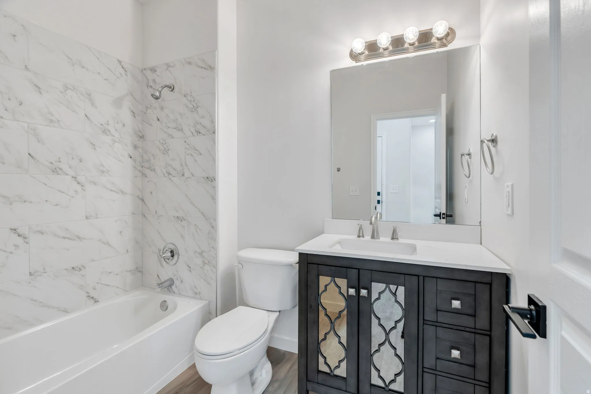 Full bath featuring vanity, bathing tub / shower combination, and wood finished floors