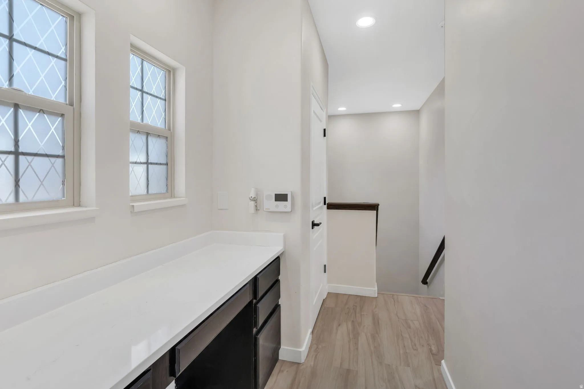 Bathroom with light wood-type flooring, vanity, and recessed lighting