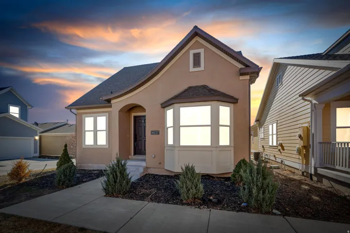 View of front of house with stucco siding and roof with shingles