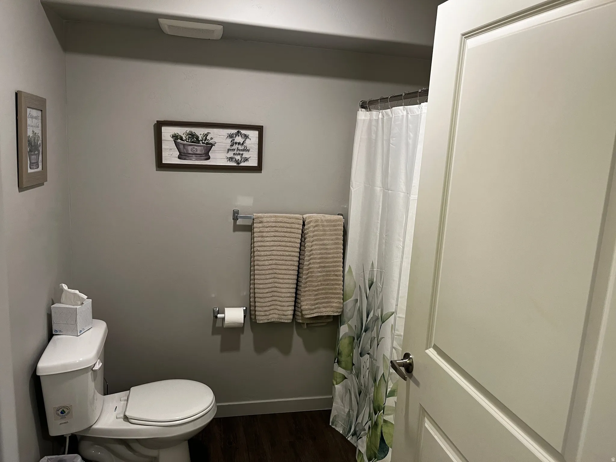 Bathroom featuring curtained shower and dark wood-style flooring