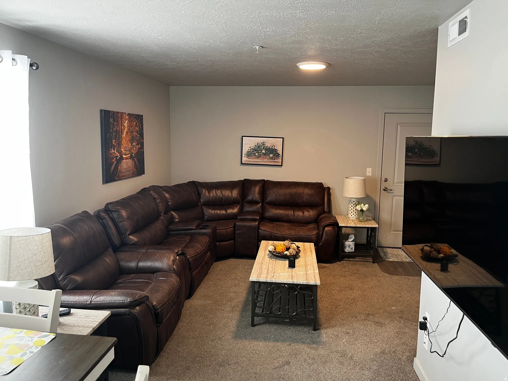 Living area with carpet flooring and a textured ceiling