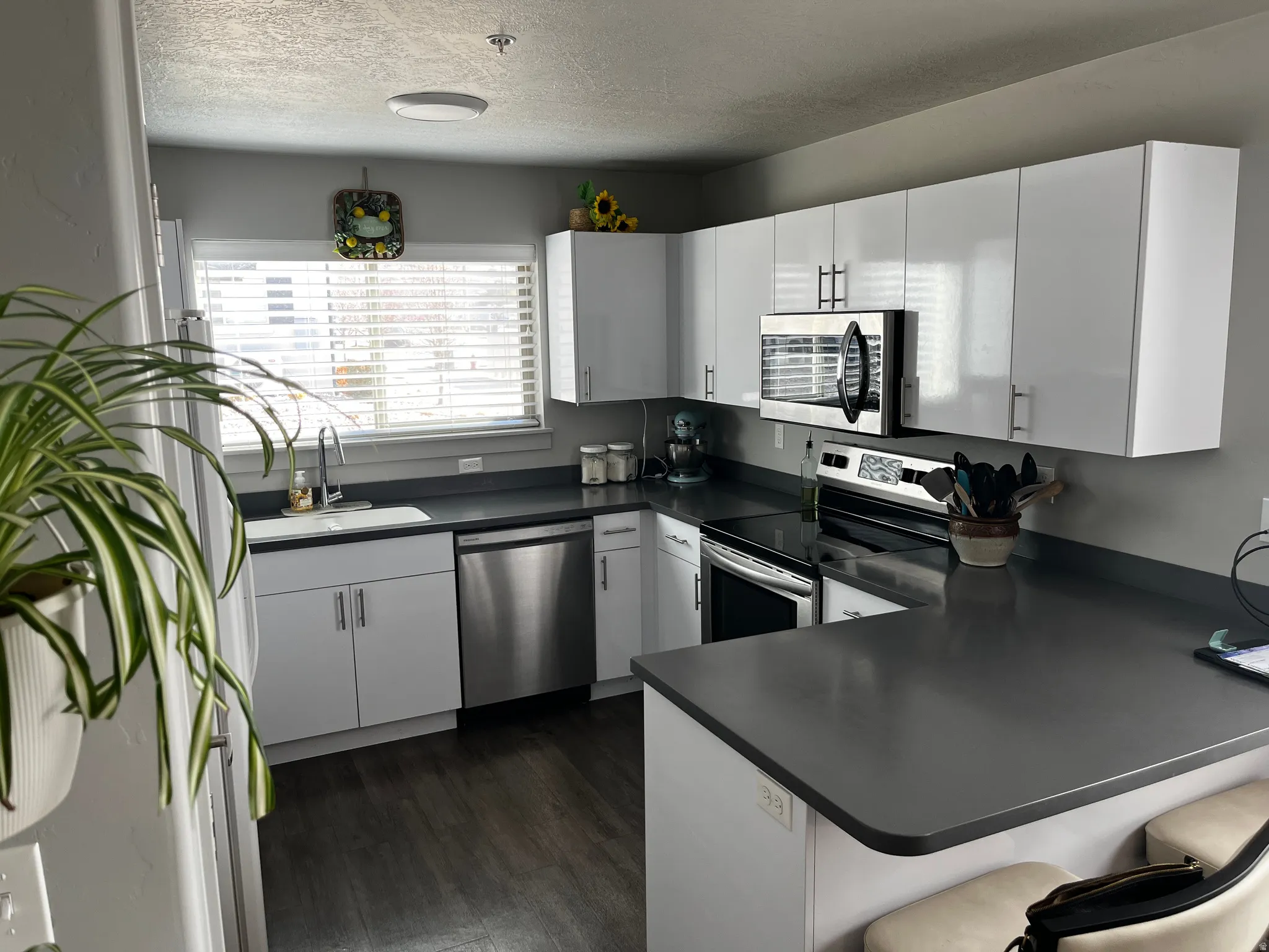 Kitchen with appliances with stainless steel finishes, a peninsula, a breakfast bar area, white cabinets, and a textured ceiling