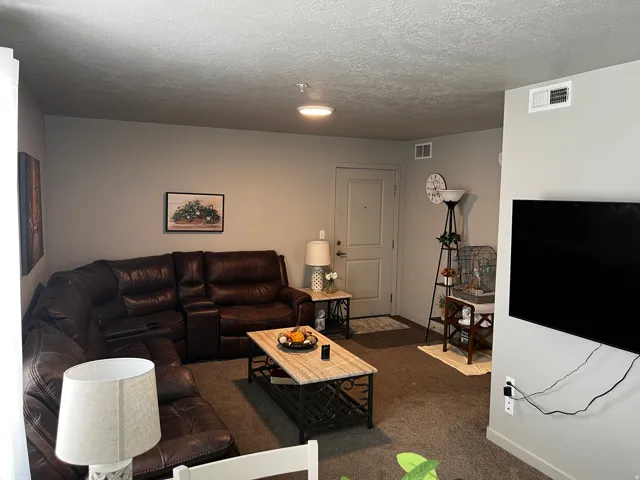 Living room with dark colored carpet and a textured ceiling