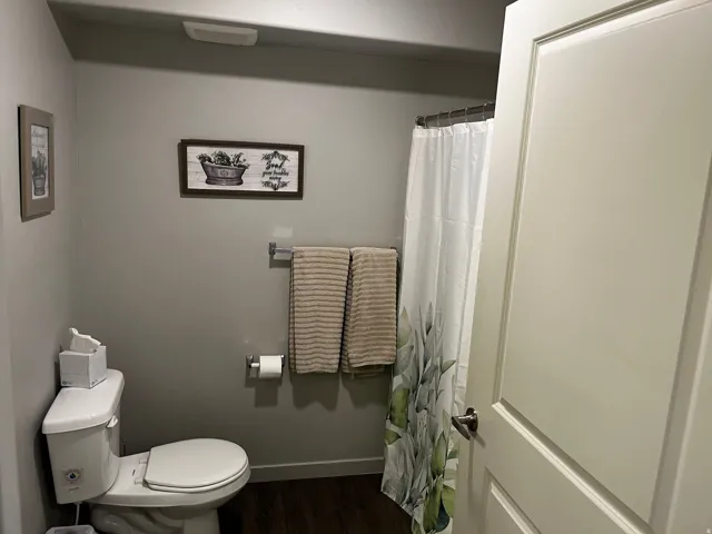 Bathroom featuring curtained shower and dark wood-style flooring