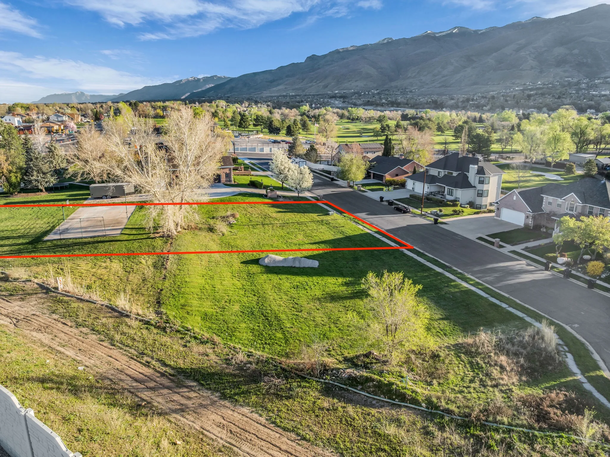 Aerial perspective of suburban area featuring property boundaries highlighted and a mountain backdrop