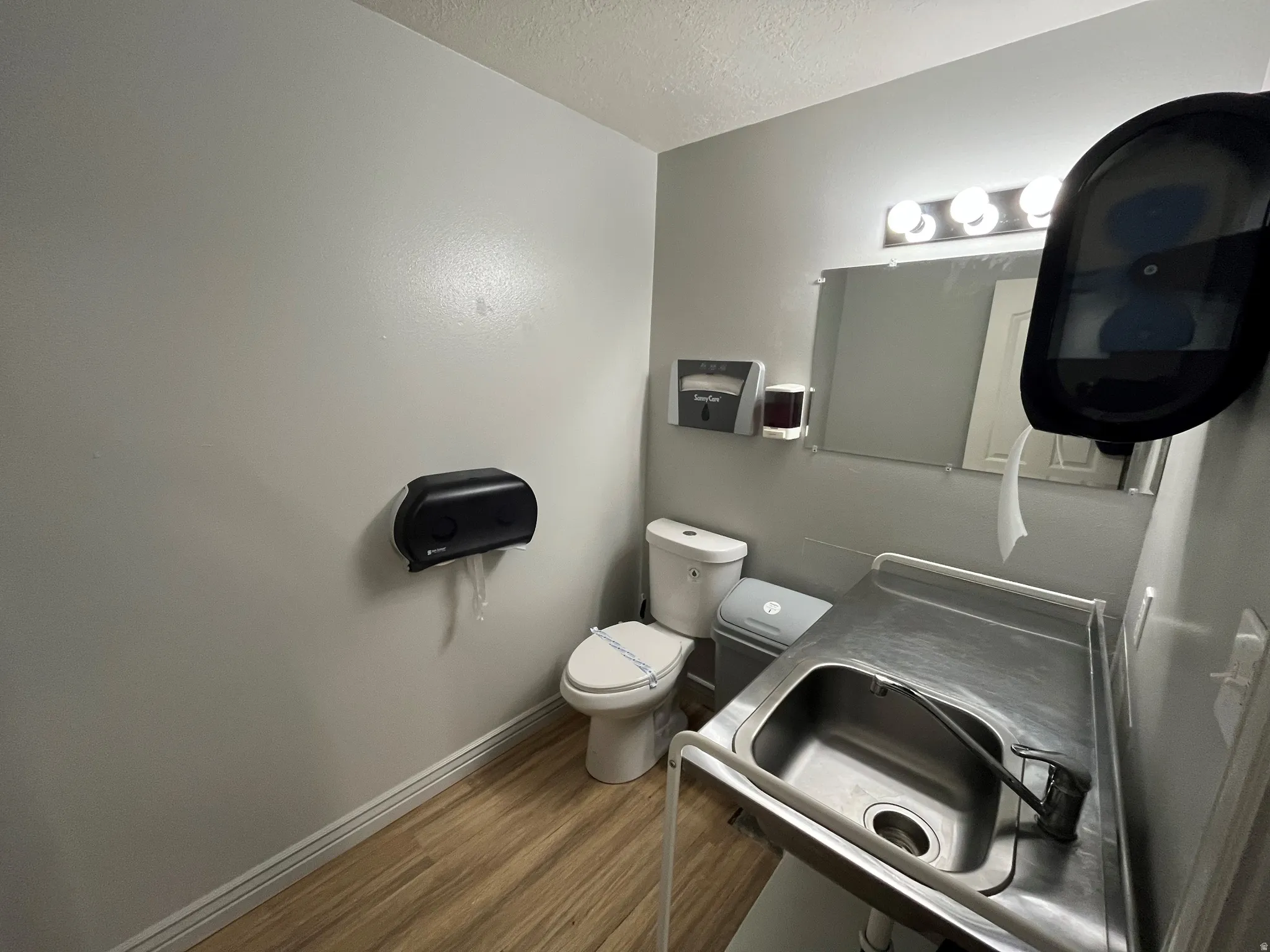 Half bath with a textured ceiling, dark wood-style floors, and vanity