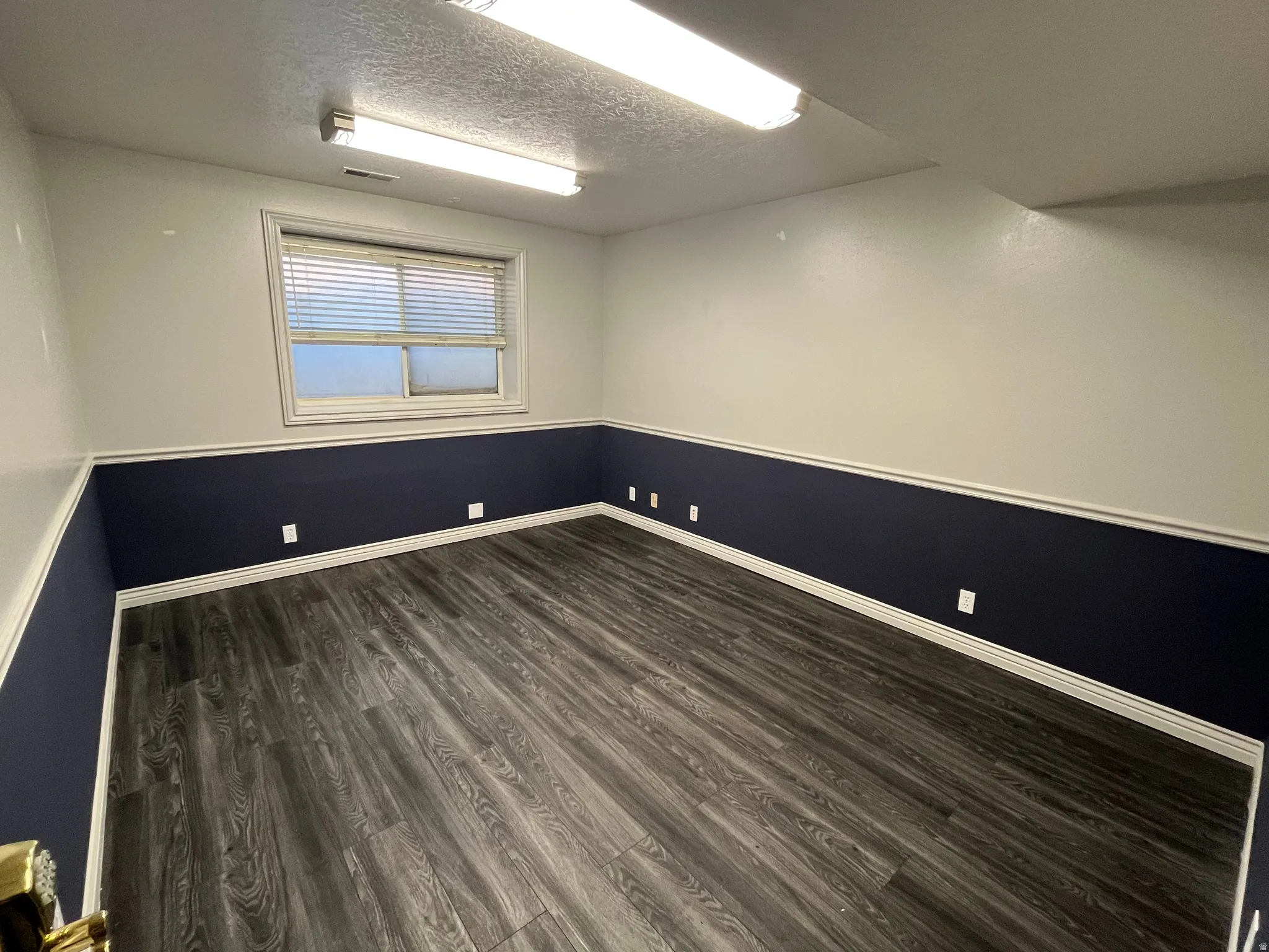 Spare room featuring dark wood-style floors and a textured ceiling