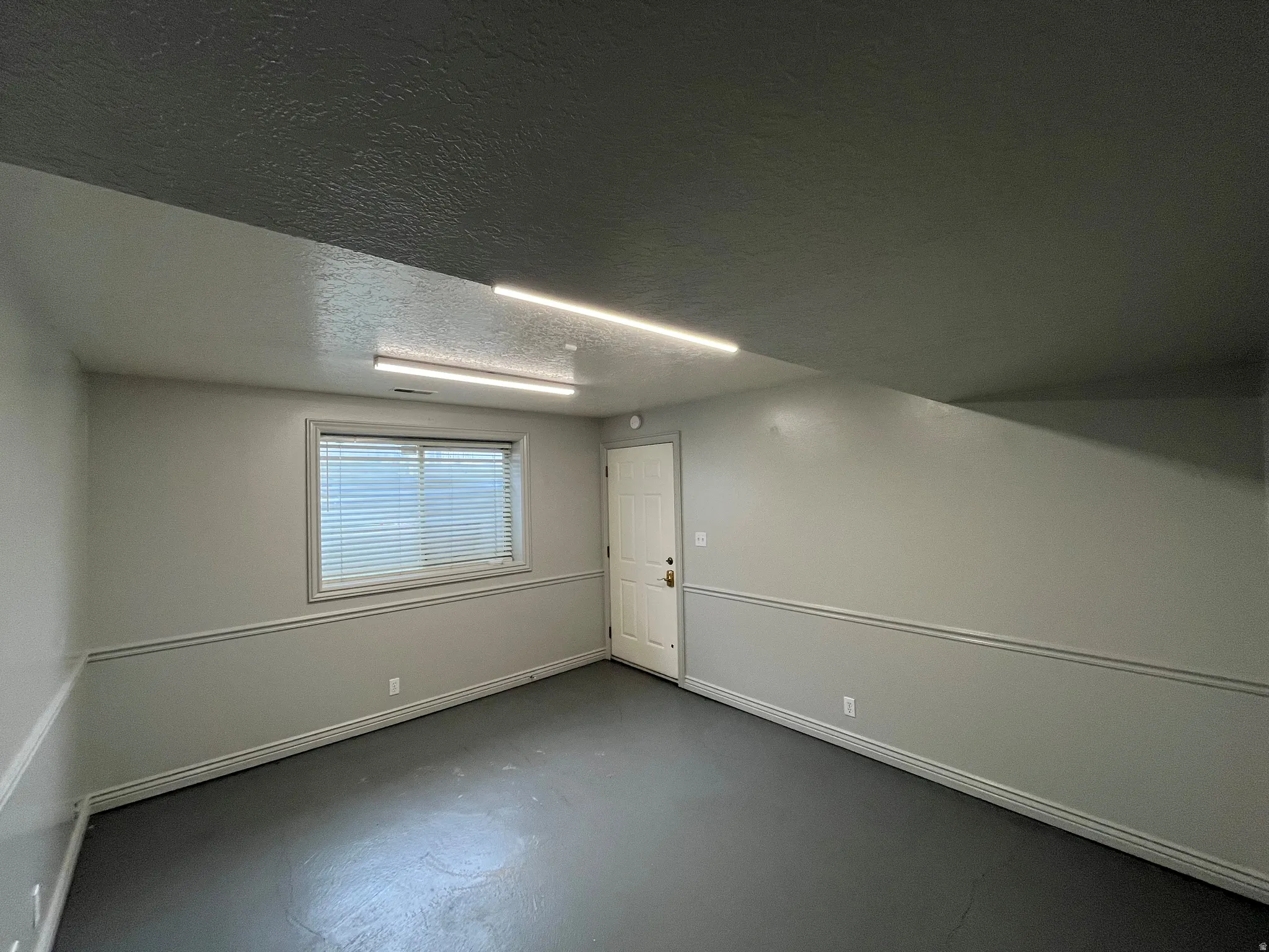 Below grade area featuring a textured ceiling and baseboards
