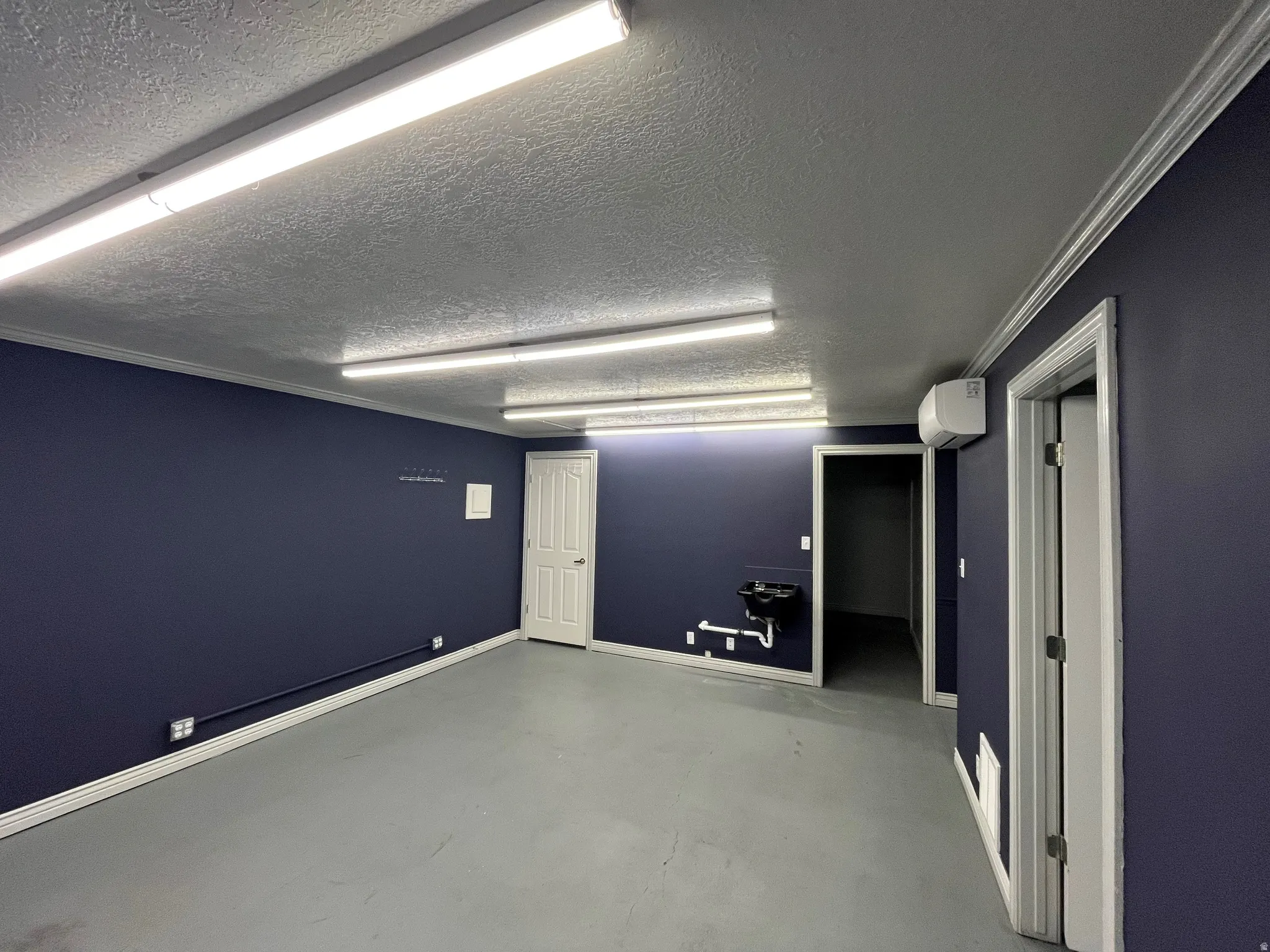 Spare room with finished concrete floors, a textured ceiling, and crown molding