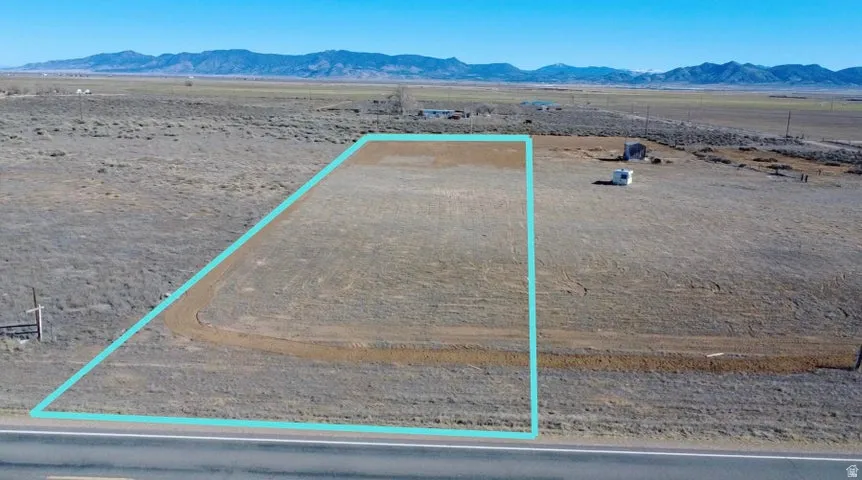 Aerial view of sparsely populated area with property parcel outlined and a mountainous background