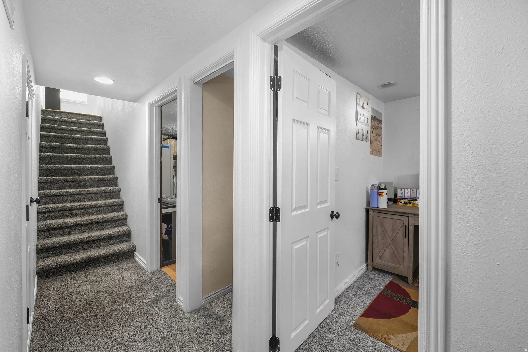 Hallway with light carpet and a textured ceiling